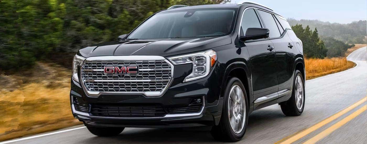 Black 2023 GMC Terrain Denali driving down an open road.