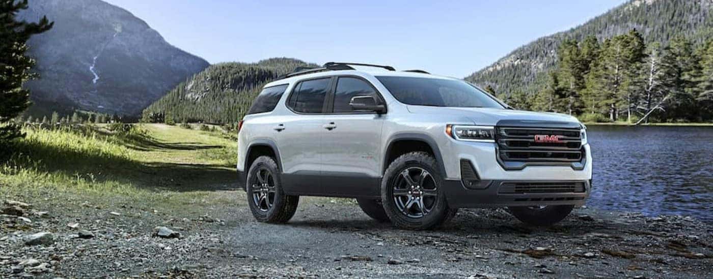 A white 2023 GMC Acadia AT4 parked near a lake.