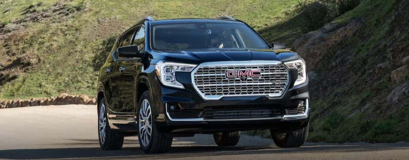 A black 2024 GMC Terrain driving to a used car dealer near me.
