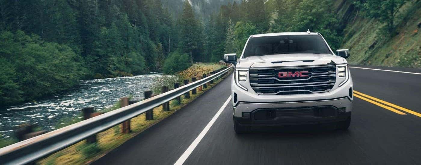 A white used 2024 GMC Sierra 1500 SLE driving down a road