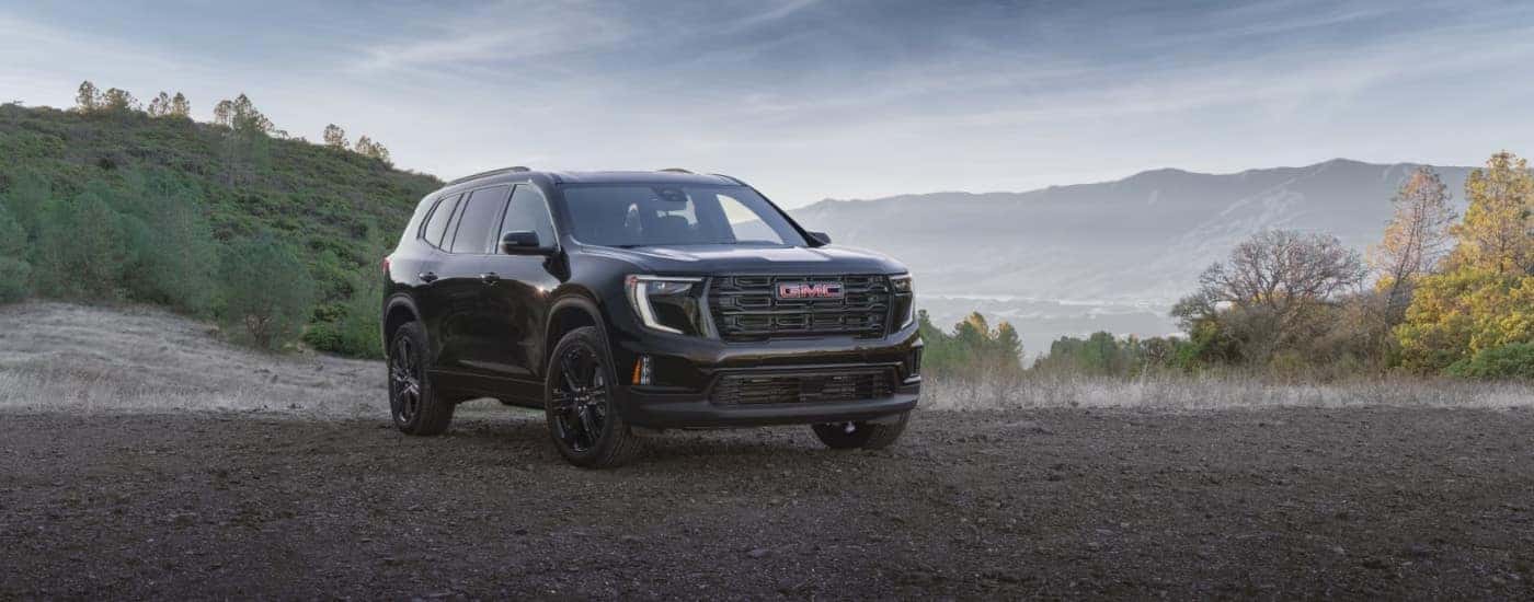 A black 2025 GMC Acadia Elevation parked off-road on gravel