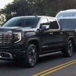 Black 2025 GMC Sierra 1500 Denali towing a silver camper