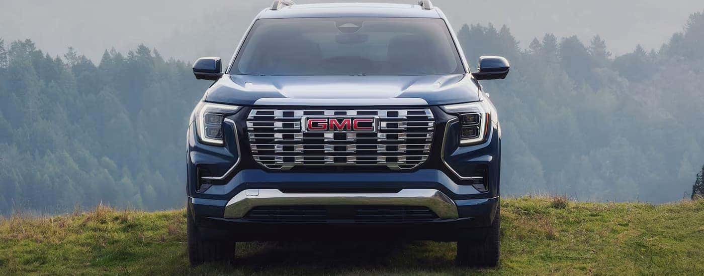 A blue 2026 GMC Terrain Denali parked on grass