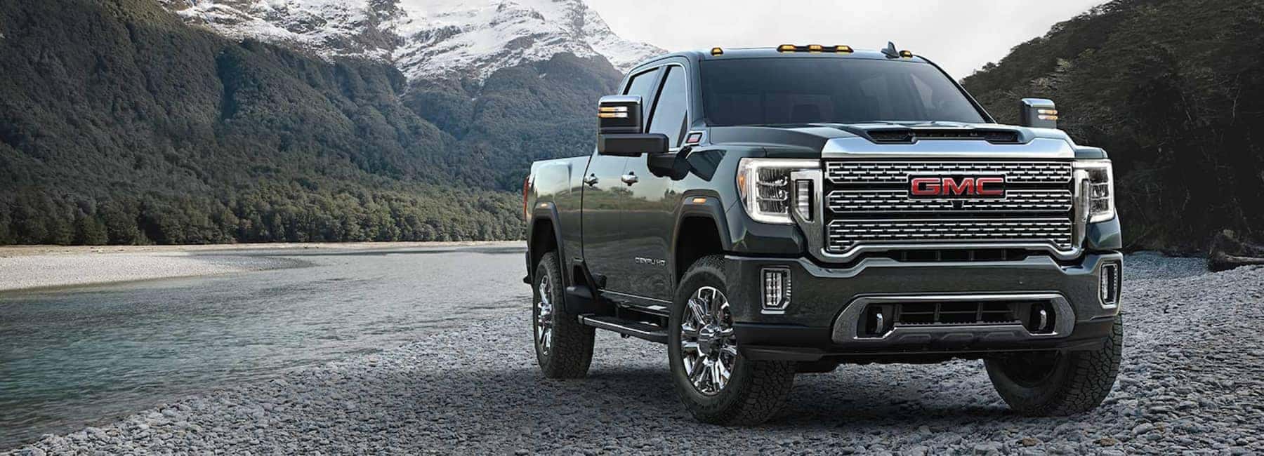 A green 2023 GMC Sierra Heavy Duty parked near a river.