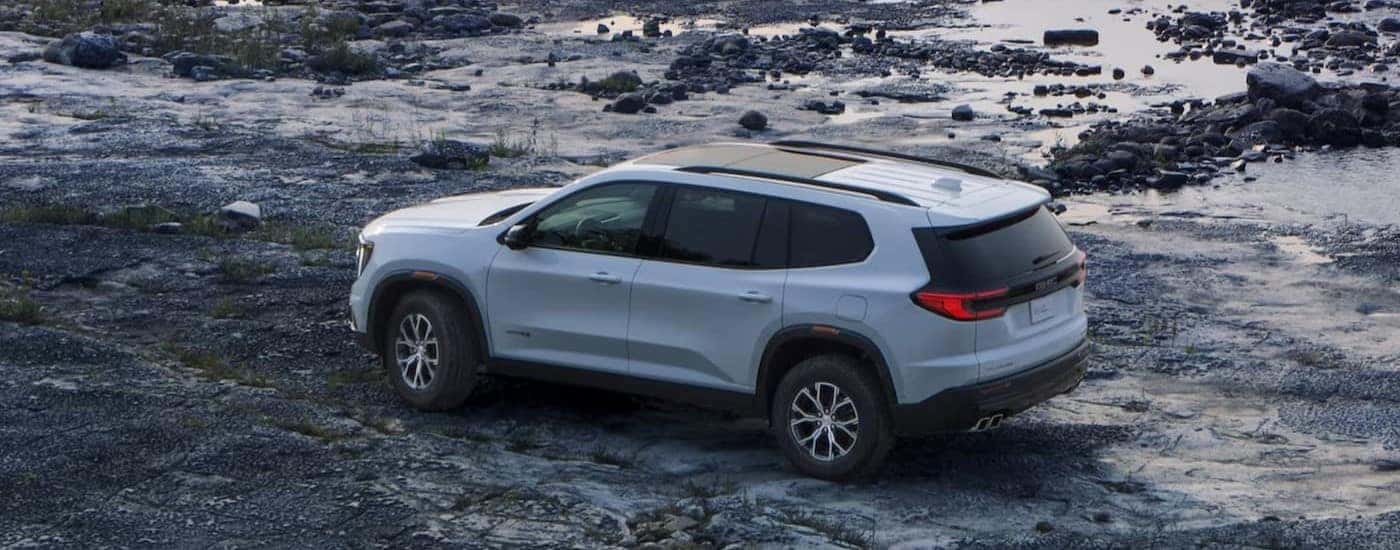 A white 2024 GMC Aacadia AT4 is shown parked off-road.