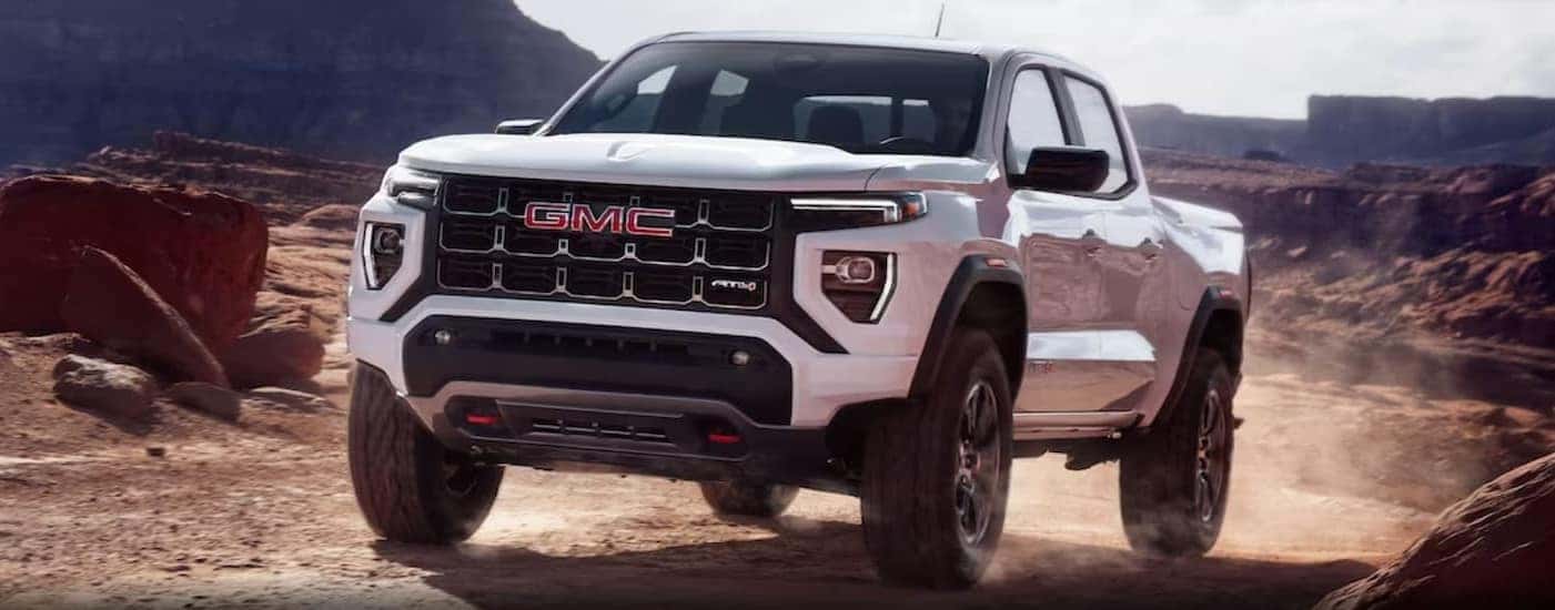 A white 2024 GMC Canyon AT4 is shown driving off-road.