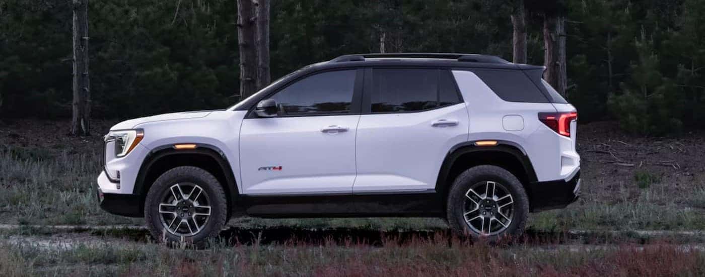 A white 2025 GMC Terrain AT4 is shown parked off-road.