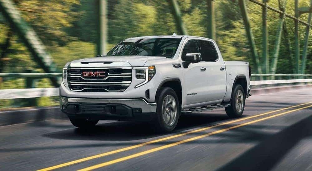 A white 2024 GMC Sierra 1500 Pro driving across a bridge.