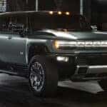 A green 2025 GMC Hummer EV for sale is parked in an alleyway.
