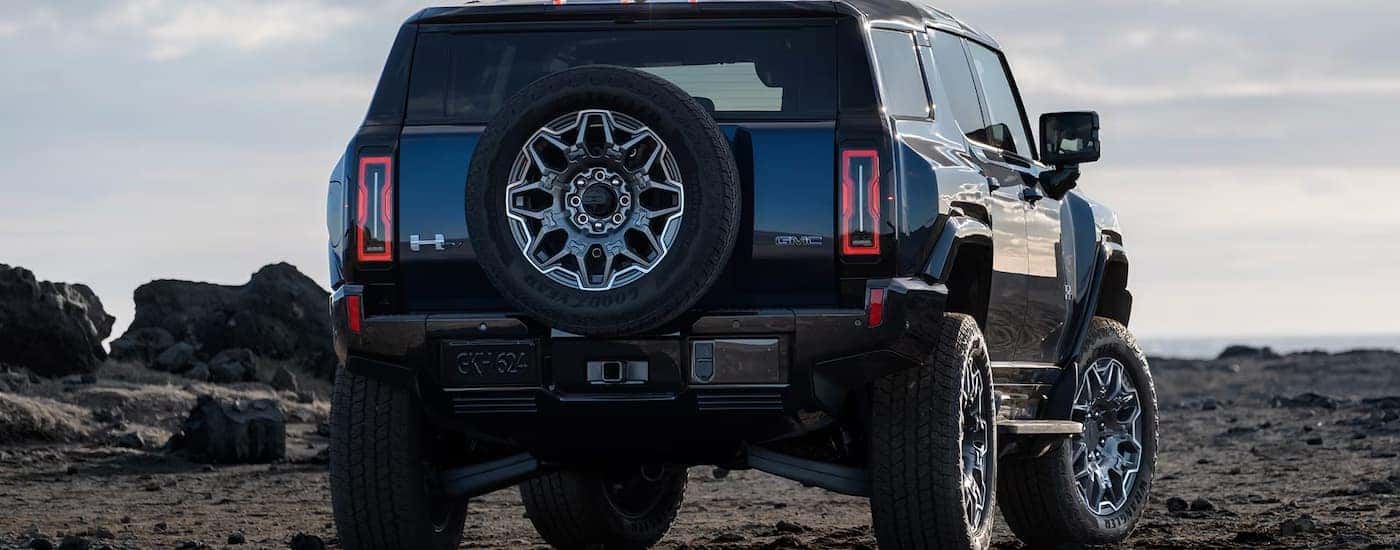 A black 2025 GMC Hummer EV SUV parked on gravel.