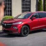 A red 2024 Buick Enclave Sport Touring parked near a house.