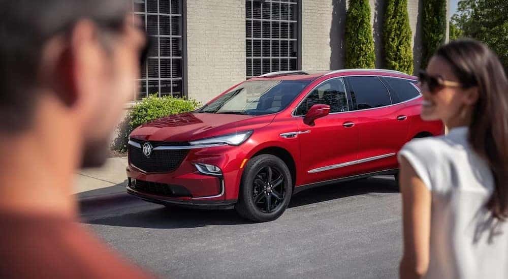 A red 2024 Buick Enclave Sport Touring parked near a house.