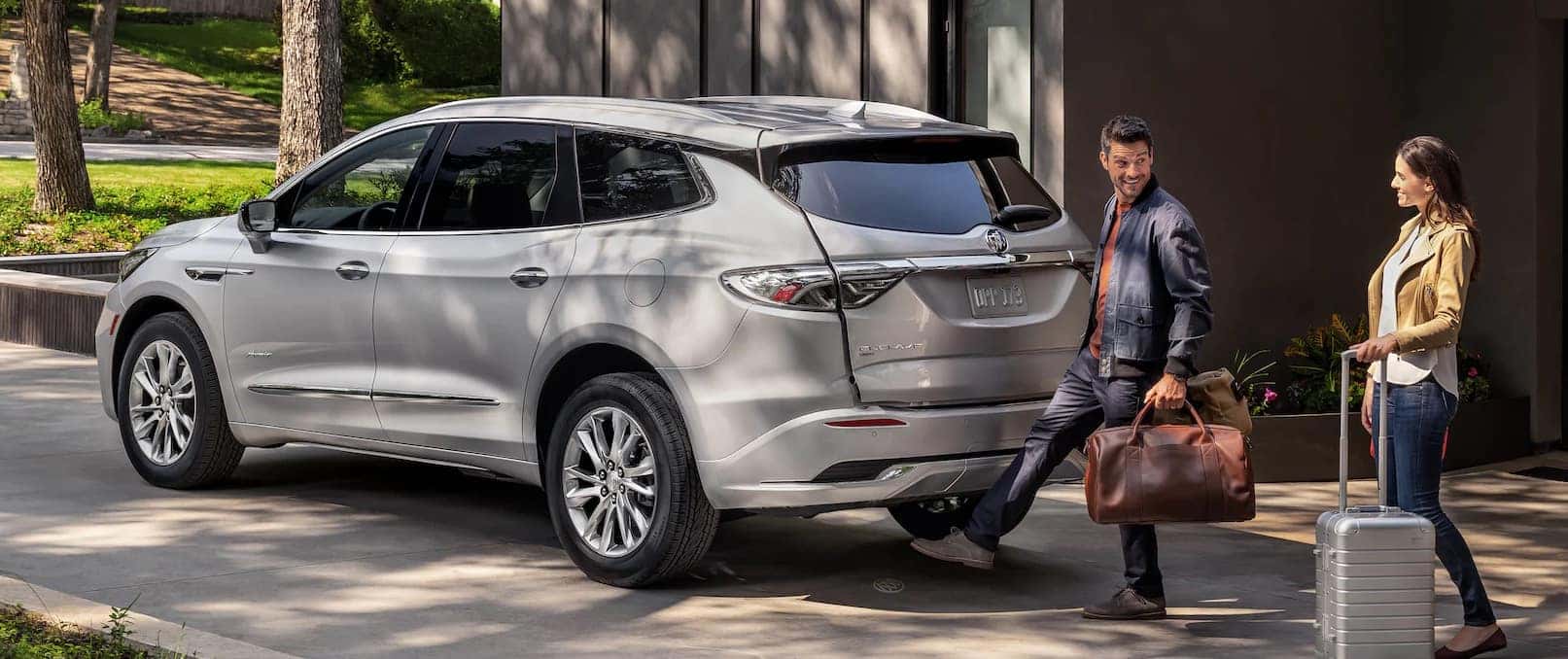 Family with luggage opening lift gate of a silver 2022 Buick Enclave.