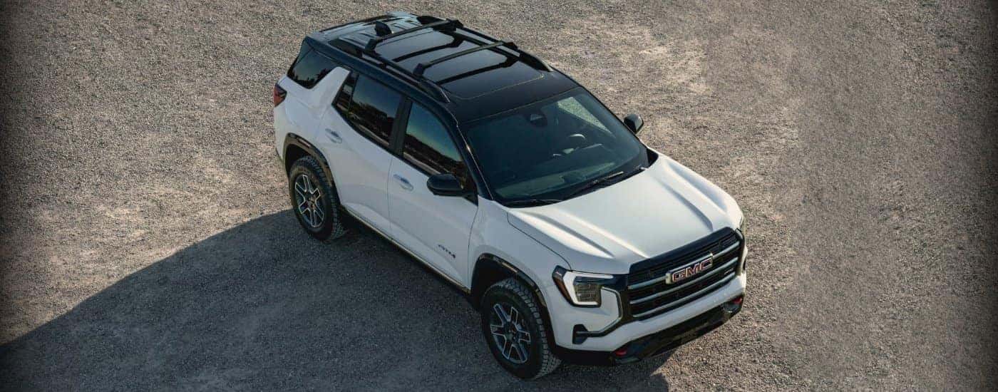 An aerial view of a white 2025 GMC Terrain AT4 is shown parked off-road.