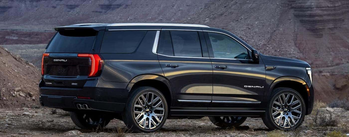A black 2025 GMC Yukon Denali parked off-road.