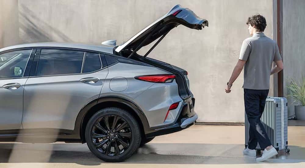 A person walking to an open tailgate in a silver 2025 Buick Envista.