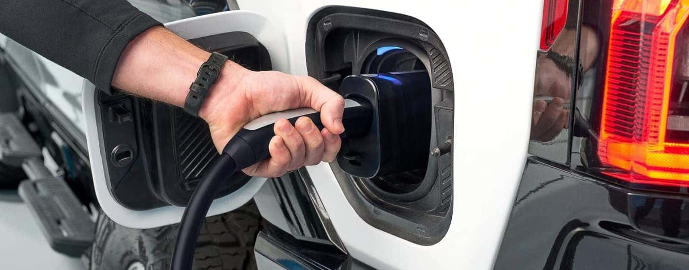 A white 2025 GMC Hummer EV plugged in to charge EV for sale in Greenville