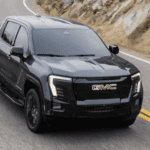 Black 2026 GMC Sierra Elevation driving down mountain road.