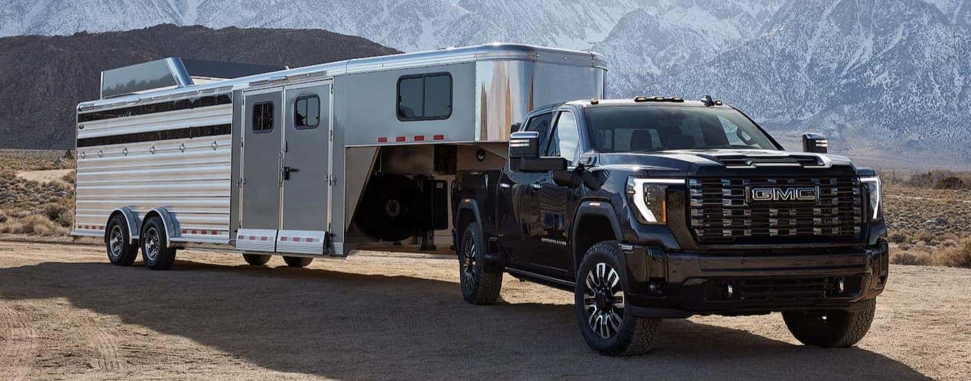 A black 2025 GMC Sierra 3500 parked while towing a trailer.