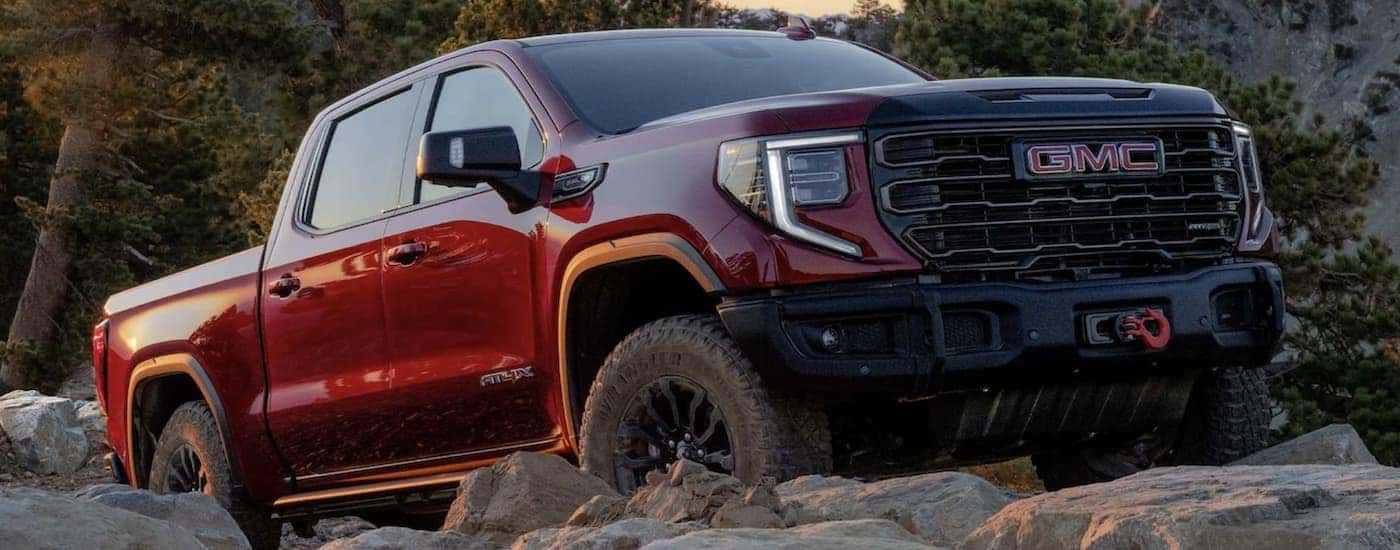 Red 2023 GMC Sierra 1500 AT4X driving across rocks off-road