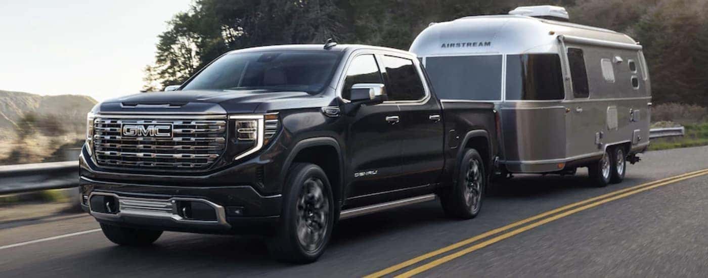 Black 2023 GMC Sierra towing a camper to look at GMC Sierras for sale near Spartanburg