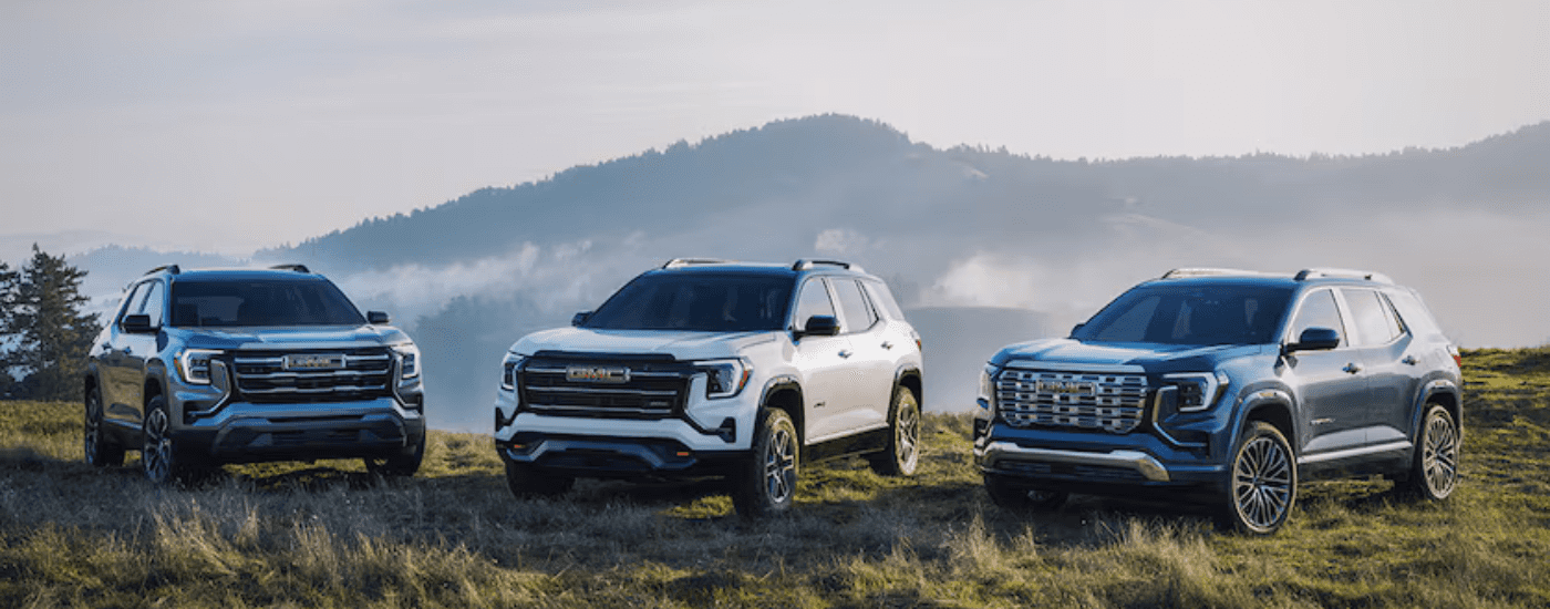 A black, a white and a blue 2026 GMC Terrain trio parked off road