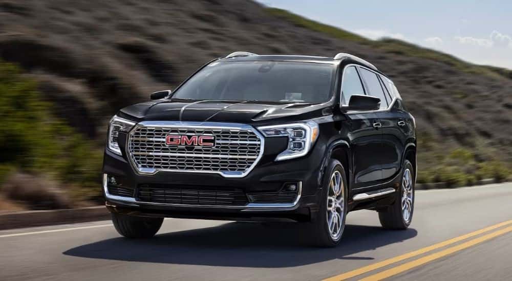 A black 2024 GMC Terrain Denali driving on a highway