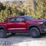 A red 2023 Chevy Colorado ZR2 is on a dirt road in the mountains.