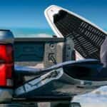 The open tailgate on a silver 2025 Chevy Colorado Z71 near a surfer.
