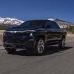 A black 2024 Chevy Silverado EV RST driving on a highway.