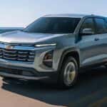 A silver 2026 Chevy Equinox driving near a lake.