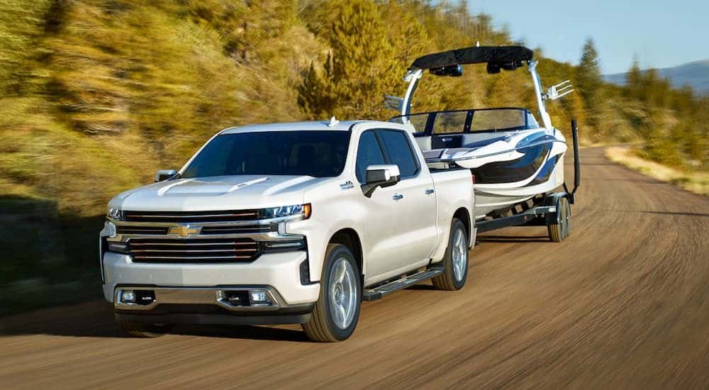 A white 2021 Chevy Silverado 1500 towing a boat.