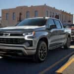 Silver 2026 Chevrolet Silverado LD for sale near Houston driving on a city road.