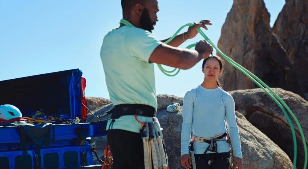 Rock climber coiling rope near a blue 2026 Chevy Silverado 1500 ZR2