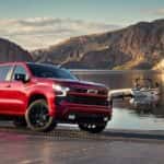 A red 2024 Chevy Silverado 1500 RST is parked near a lake.