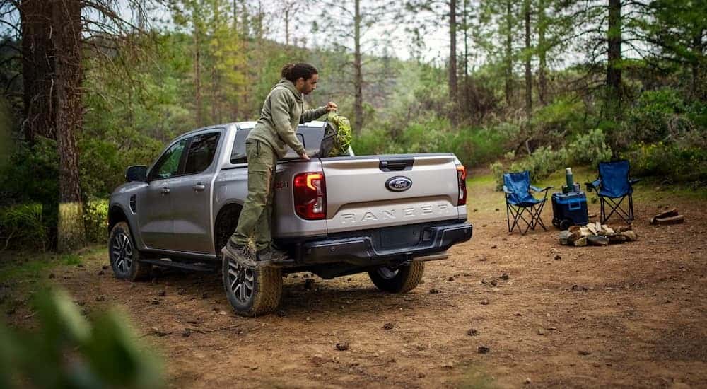 A man utilizing the boxside step to access camping gear in the bed of a 2024 Ford Ranger.