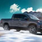 A grey 2021 Honda Ridgeline RTL-E driving across a snowy plain.