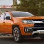 An orange 2021 Chevy Colorado Z71 driving to a used truck dealer near Katy.