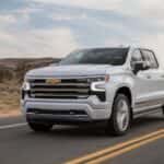A white 2023 Chevy Silverado High Country is shown from the front at an angle.