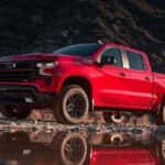 A red 2024 Chevy Silverado 1500 Z71 Trail Boss is shown from the front at an angle after leaving a Chevy Silverado dealer.