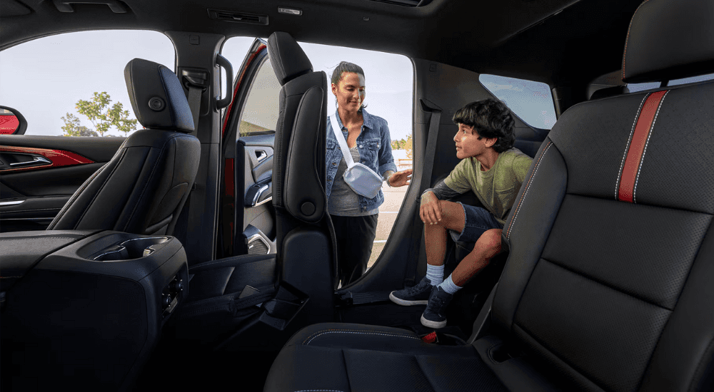 A parent helps their child get out of the third row of a 2026 Chevy Traverse