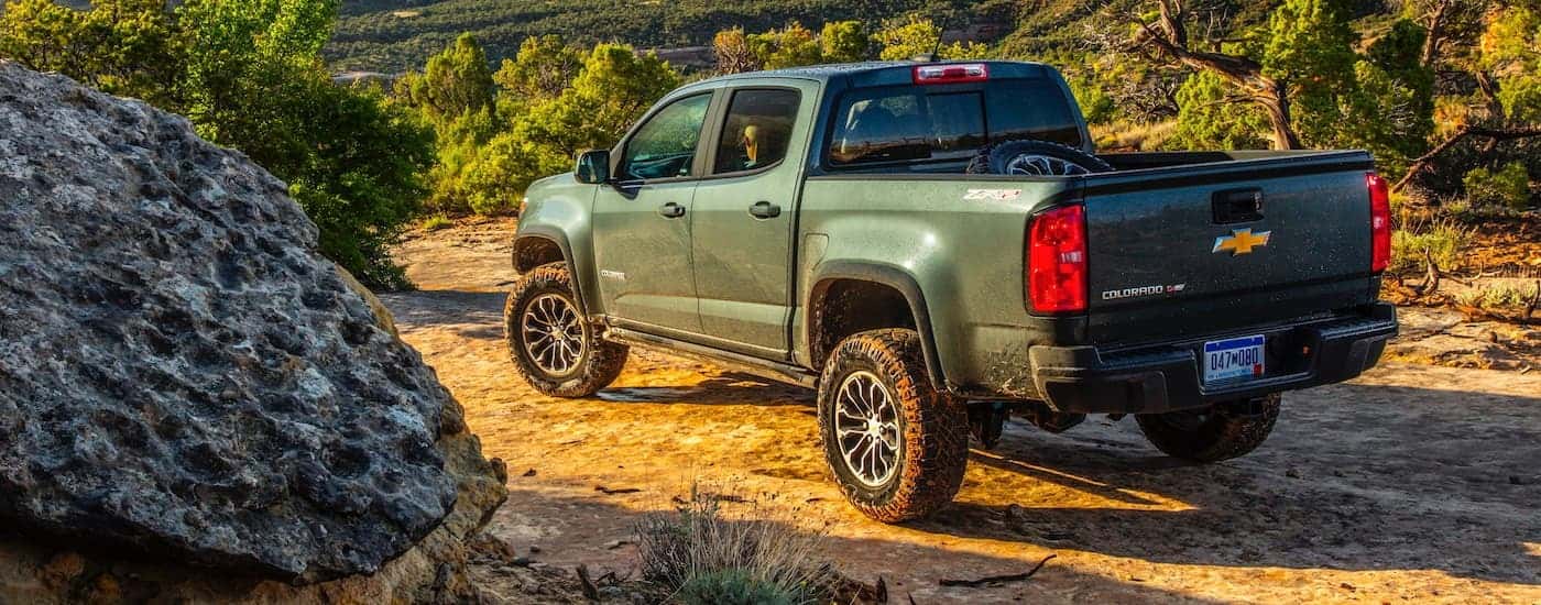 A green 2020 Chevy Colorado is shown from the rear parked on a dirt trail