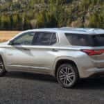 A white 2022 Chevy Traverse High Country is parked in front of yellow grass and mountains.
