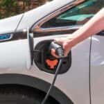 A popular Chevy EV, a white 2020 Chevy Bolt EV, is shown being charged.