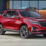 A red 2022 Chevy Equinox RS is shown parked in front of a glass building.
