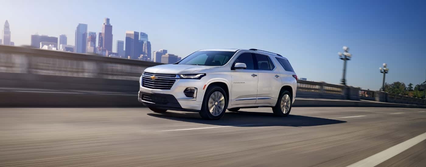 Silver 2023 Chevy Traverse driving past a city