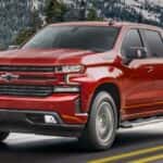 A red 2021 Chevy Silverado 1500 is shown from the side driving on an open road.