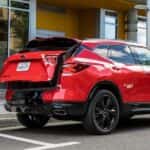 A man is shown opening the lift gate on a red 2020 Chevy Blazer RS.