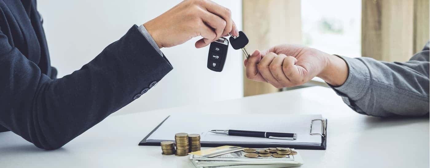 A customer and car salesman are shown exchanging a car key