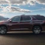A brown 2023 Chevy Traverse High Country is shown from the side driving on an open highway.